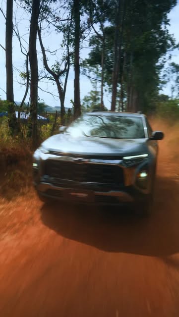 Chevrolet Equinox em movimento numa estrada de terra entre árvores